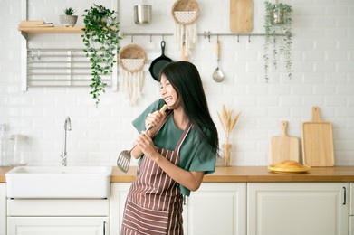 asian young woman dancing in kitchen room. she happy and relaxing at free time on weekend