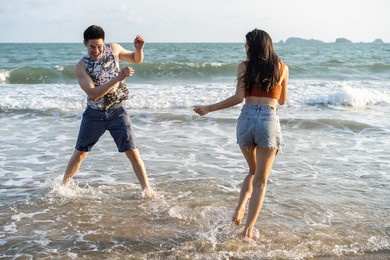 blurred of asian young man and woman having fun on the beach together. attractive new marriage people feel happy while walk and running at seaside enjoy holiday honeymoon trip in tropical sea island.