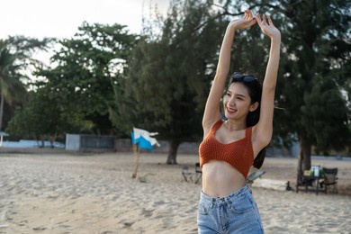 asian young beautiful woman walking slowly on beach during summer time. attractive girl traveler feel happy and relax taking a deep breath while travel for holiday vacation trip in tropical sea island