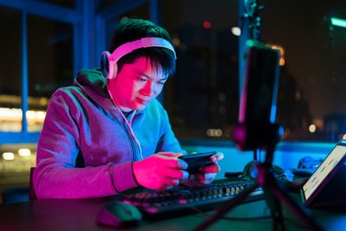 asian male esports gamer playing online sport leagues multiplayer game via smartphone with exited and cheerful emotion,asian male wear headset playing smartphone game online together with friends
