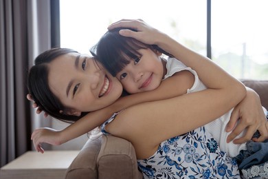 asian mother and daughter smile and look at camera. happy love family concept