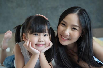 asian mother and daughter smile and look at camera. happy love family concept