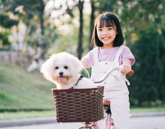 image of asian little girl cycling with her pet dog at the park