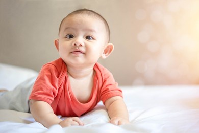 happy family, cute asian newborn baby wear red shirt lying, crawling, play on white bed with laughing smile happy face. little innocent infant adorable child in first day of life. mother day concept.