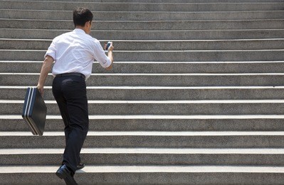 businessman holding mobile and in hurry to run up on stairs