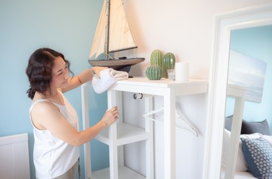 positive asian woman housewife tidying modern home. happy woman doing domestic chores. asian housewife wiping shelf, furniture, bed, mirror, sofa, and home appliances.