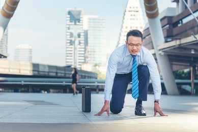 asian man look at camera smile face wear glasses. man happiness time start up a business goal. businessman race concept. businessman start kneeling city street race business goal winner challenge