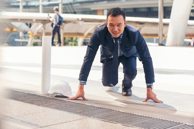 businessman start kneeling city street race business goal winner challenge. asian man look at camera smile face wear glasses. man happiness time start up a business goal. businessman race concept