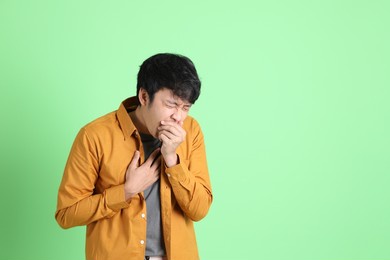 the young adult asian man with smart casual clothes standing on the light green background.