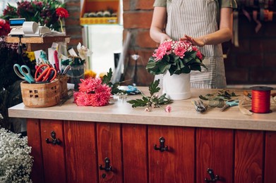 young blonde florist woman creating flower arrangement in a round box for a gift for a special occasion while working in a flower shop. beautiful bouquet of mixed flowers in a round box.