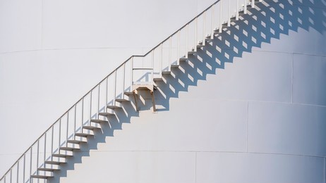 background of curve line spiral staircase on storage fuel tank with sunlight and shadow on surface 