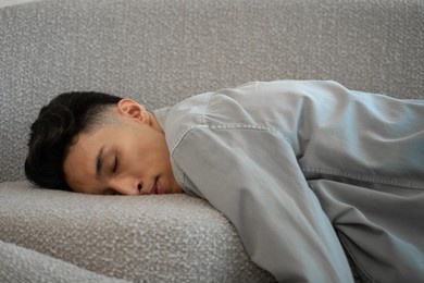 tired asian man falls down on couch falling asleep. exhausted young male person wants to relax in living room after hard working day close view