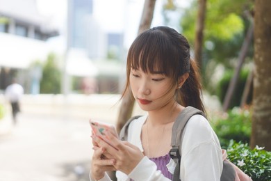 college people education lifestyle work and study on day time concept. young adult asian female student using digital mobile phone for online message at outdoor.