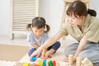 asian little girl playing with the building blocks with her mother