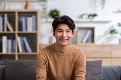 asian handsome man looking at camera smile at home.happy young smart businessman smile and confidence.positive and good moment of asian male worker smile  with wellness life