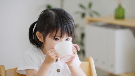 asian child drinking water in  the living room
