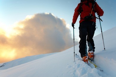 backcountry skier walks in the snow at sunset, italian alps, europe.