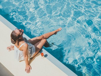 fashionable woman sitting by the pool on the empty deck of a cruise liner. closeup, outdoor, view from above. vacation and travel concept