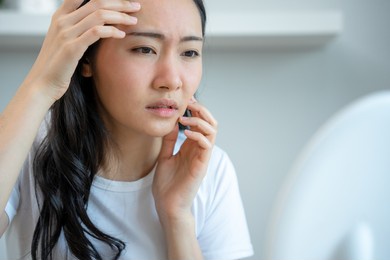 young woman asian are worried about faces dermatology and allergic to steroids in cosmetics. sensitive skin,red face from sunburn, acne,allergic to chemicals,rash on face. skin problems and beauty