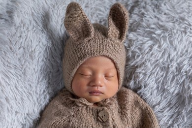 happy newborn baby wearing cute rabbit costume lying sleep on grey carpet background comfortable and safety.cute asian infant sleeping and napping on baby bed.newborn baby easter day concept
