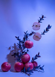 a composition of red apples with green leaves on a blue background. neon colors. a summer picture with a place for the test.