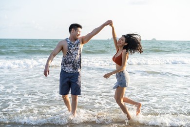 blurred of asian young man and woman having fun on the beach together. attractive new marriage people feel happy while walk and running at seaside enjoy holiday honeymoon trip in tropical sea island.