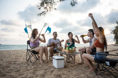group of asian young man and woman having party on the beach together. attractive happy friends traveler singing and dancing while camping at seaside enjoy holiday vacation trip in tropical sea island