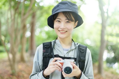 portrait of young asian woman using digital camera in a forest