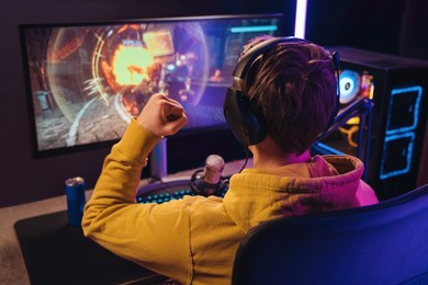 back view of streamer young man rejoices his victory in esport shooter game tournament, making winner hand gesture. professional gamer streaming online gameplay competition. cyber sport concept
