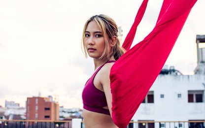 beautiful healthy strong woman wearing sport bra, relaxing, exercise yoga fly, aerial silk on outdoor rooftop in morning. there are background of sky, sunlight flare, copy space advertisement
