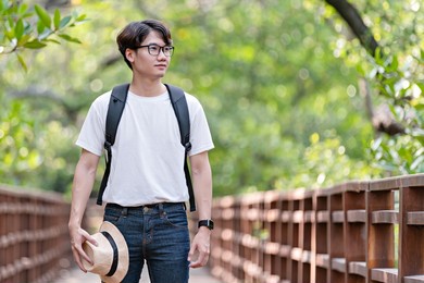 happy man travel mangrove forest. tourist traveler wear white shirt with hat for backpack activity. asian man ready to go hiking. relax time on holiday concept travel.