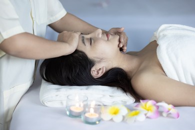 happy relaxing asian girl at beauty spa treatment. beauty young asian woman recieving massage at spa, massager's hands on the woman's shoulder spa concept. young woman with glow, and perfect skin.