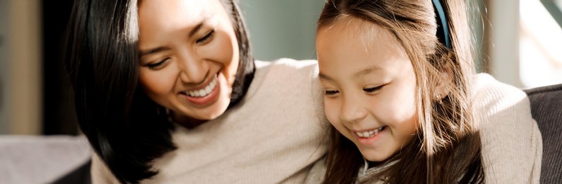 young asian woman smiling while spending time with her daughter at home