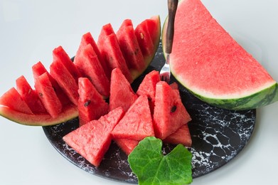 sliced fresh red flesh melon fruit in black plate on white background