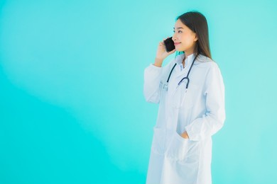 portrait beautiful young asian doctor woman use mobile smart cell phone for clinic or hospital on blue isolated background