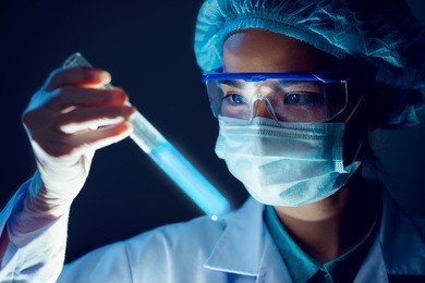 medical researcher holding test tube with blue fluorescent liquid