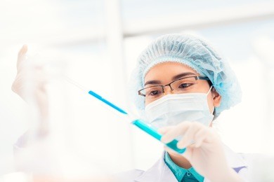 asian researcher dropping reagent into test tube