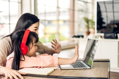 mother and asian kid little girl learn and look at laptop computer reviewing lesson study with online education e-learning.student look for educational knowledge in homeschool at home.education