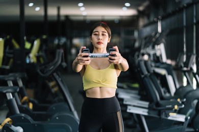 beautiful young asian woman doing exercises in gym to stay fit. fit female exercising with dumbbell weights.