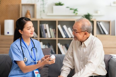 a doctor who works in an office and consults to patient, she explains health care symptoms and help elderly man, giv medicines. writing down diagnosed and symptoms, elderly care, health care concept.