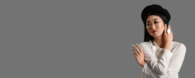 portrait of fashionable asian woman with painted face on grey background with space for text