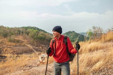 young asian man mountaineering wearing jacket walking at outdoor. tourist on top of the mountain walking by trekking pole. travel adventure hiking concept.