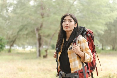 walking into the wilderness is a lovely asian backpacking woman.