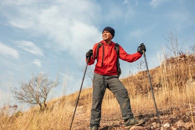 young asian man mountaineering wearing jacket walking at outdoor. tourist on top of the mountain walking by trekking pole. travel adventure hiking concept.
