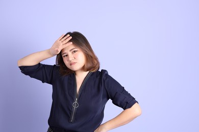the chubby asian woman standing on the purple background with the casual clothes.