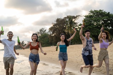 group of asian young man and woman having party on the beach together. attractive friends singing and dancing while walking and running at seaside enjoy holiday vacation trip in tropical sea island.