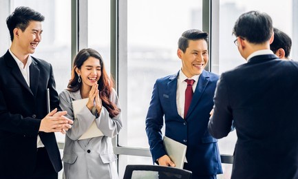 image two asian business partners in elegant suit successful handshake together in front of group of casual business clapping hands in modern office.partnership approval and thanks gesture concept