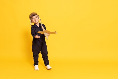 asian little boy playing with cardboard airplane isolated on yellow background