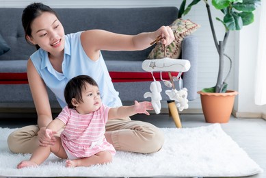 asian mother and daughter is 7 months old, sitting on the floor, and playing a toy that supports the development of children, to asian family and educational development concept.
