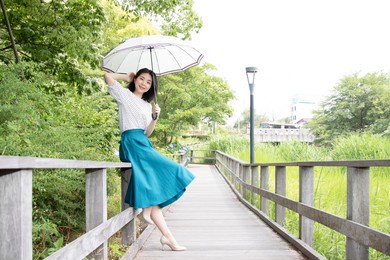 an elegant woman with a parasol is strolling in nature